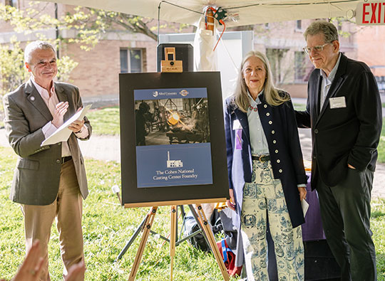 three people, two men and a woman, standing next to a sign 