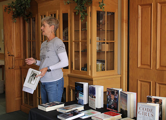woman standing by a table of books talking