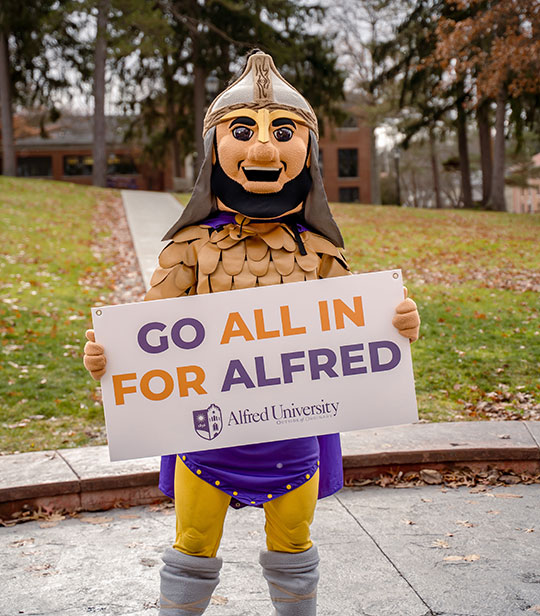 Li'l Alf mascot holding sign promoting Day of Giving