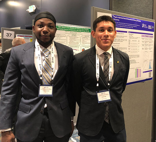 two men standing next to a poster