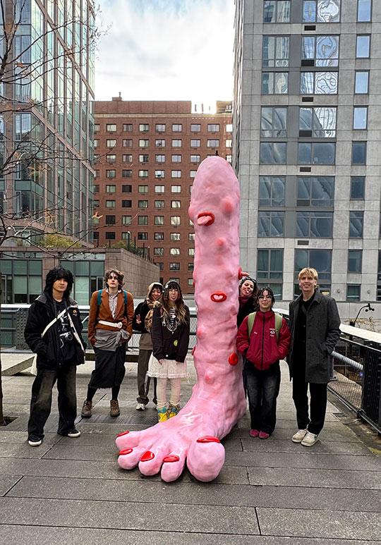 people standing around a giant sculpture of a foot