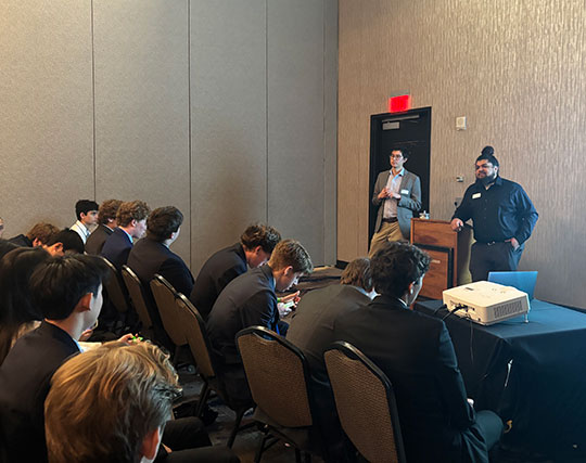 two men at a podium talking to a group of people
