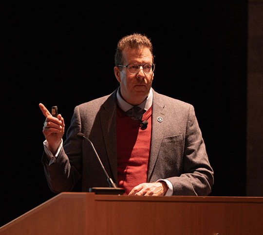 man wearing glasses talking at a podium
