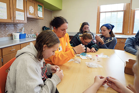 Abigail Gatza helping students assemble robots
