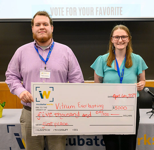 two people, man and women, holding giant check