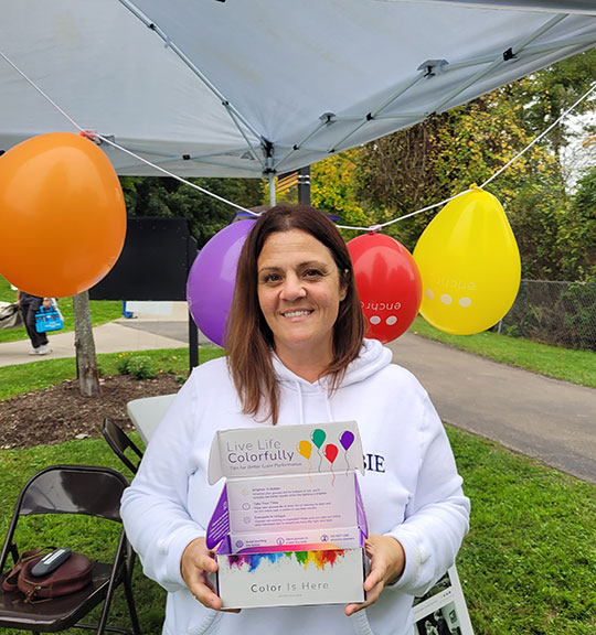 woman by a tent, holding a box