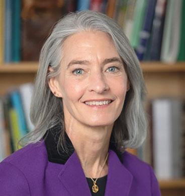 headshot of woman with silver hair, purple blouse