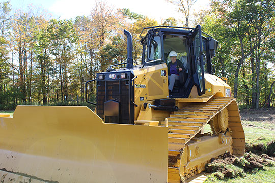 woman with glasses and hardhat operating a bulldozer 