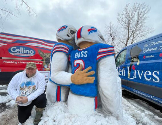 man kneeling next to snow sculpture