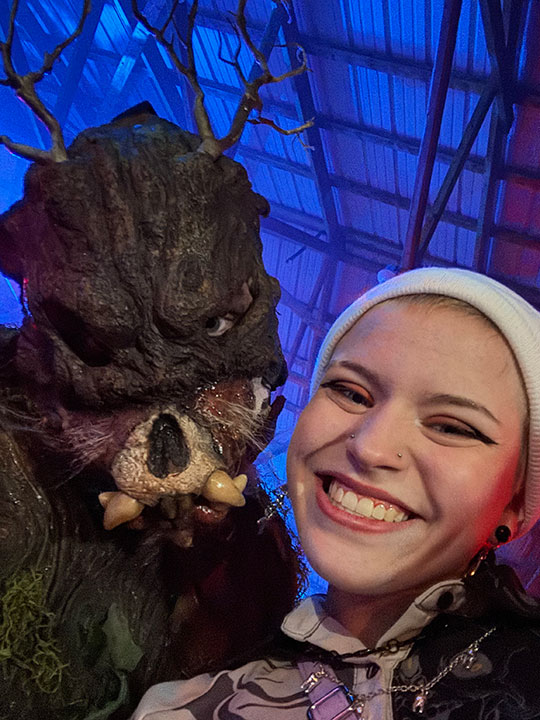 young woman smiling, with person in scary mask 