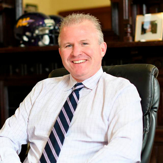 headshot of man smiling, with shirt and tie