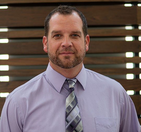 headshot of man with shirt and tie, beard