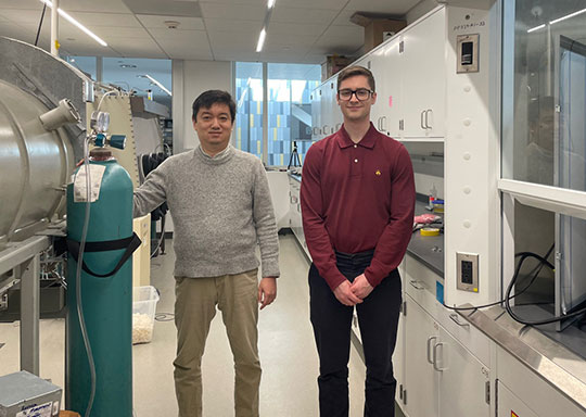 two men, a professor and a student, standing in an engineering lab