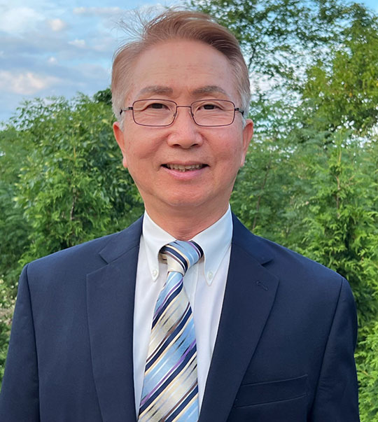headshot of man with coat and tie, glasses