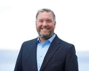 headshot of man with beard, wearing blue blazer and dress shirt