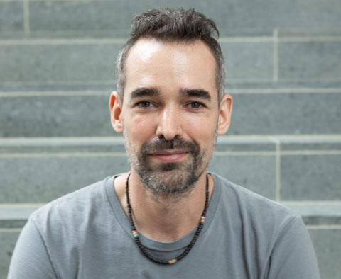 headshot of man with short hair, wearing tshirt, smiling 