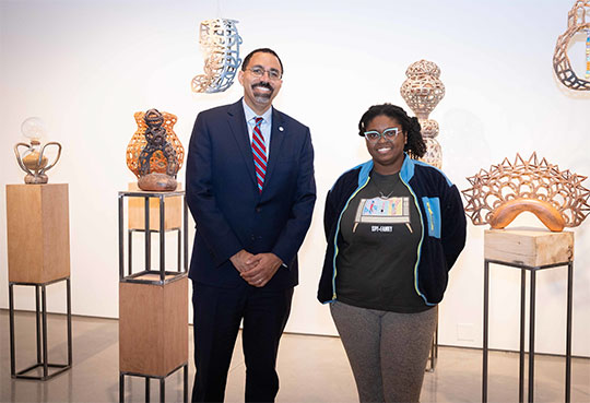 Man in shirt and tie with woman in front of art exhibit
