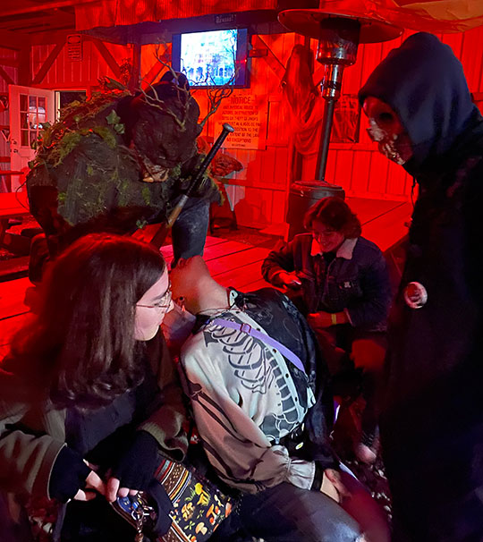 people sitting at a table with other people dressed up in scary costumes