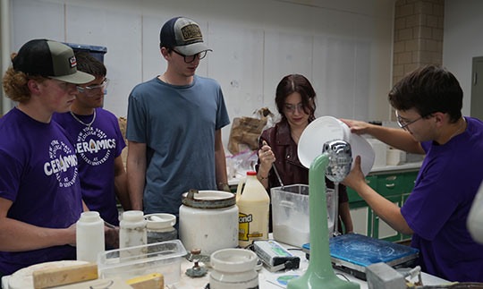 five young people at a table mixing materials