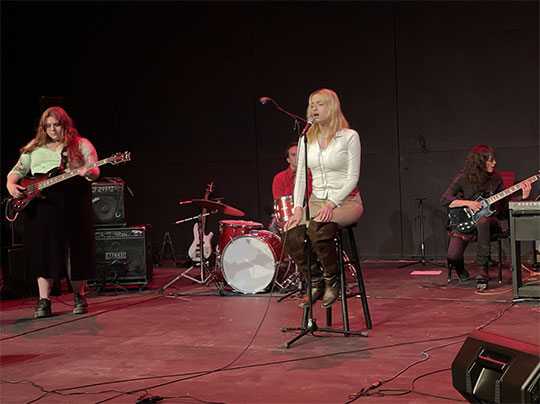 young woman on stool singing on stage