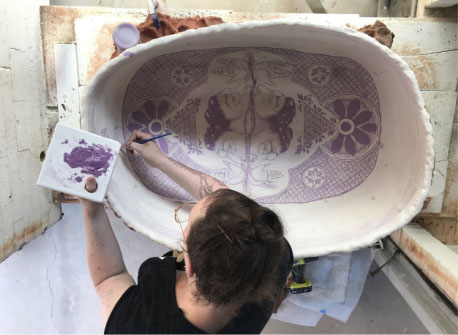 woman painting a piece of ceramic art