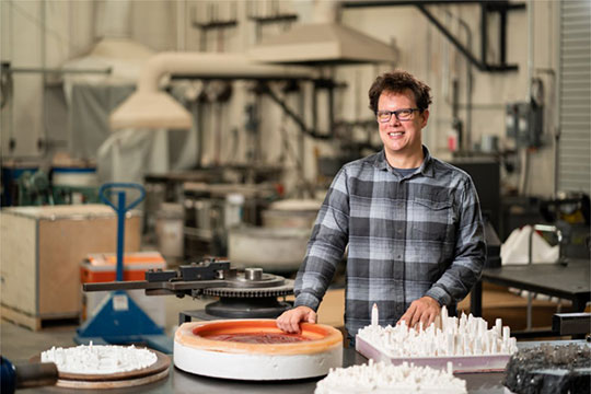man wearing glasses, in art studio with sculptures