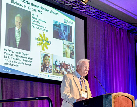 man in suit and tie speaking at podium