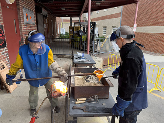 photo of two people pouring molten glass into a mold