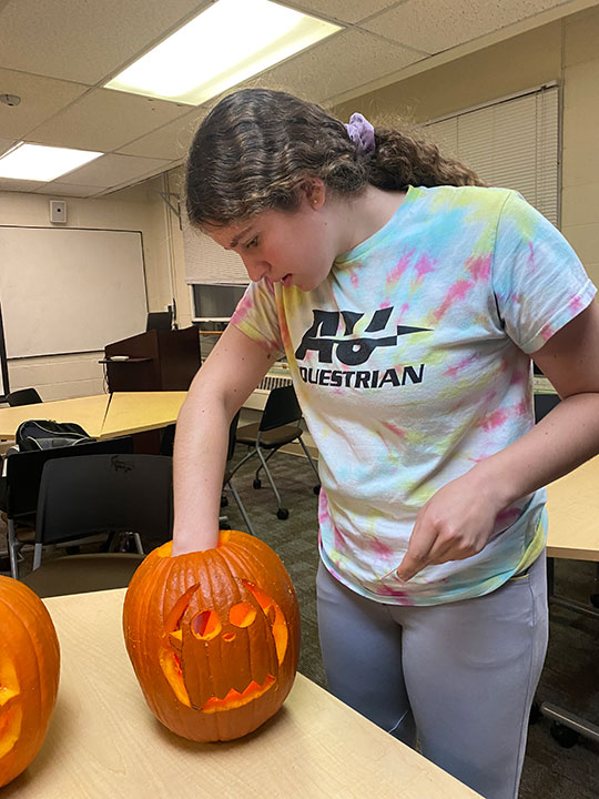 young woman carving a pumpkin