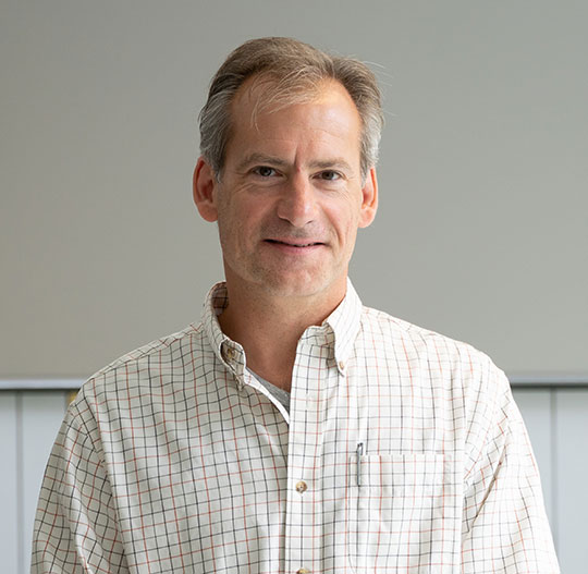 headshot of man with dark hair and dress shirt
