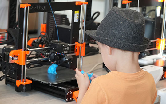 boy looking at an object made on a three-dimensional printer