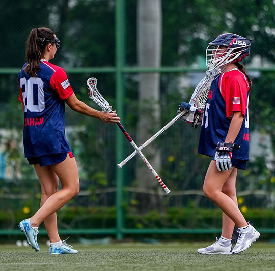 photo of two women's lacrosse players on the field