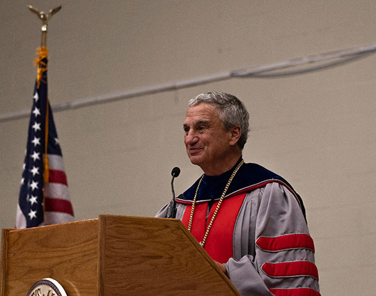 man with robe speaking at a podium