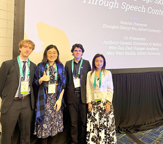group of four people, two women and two men, standing in front of a sign