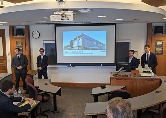 four young men in front of a screen giving a presentation