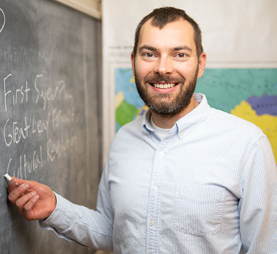 headshot of man writing on chalkboard
