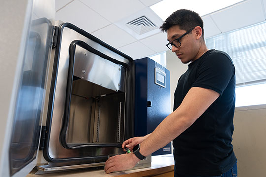 Young man in black t-shirt and glasses running a battery test using equipment