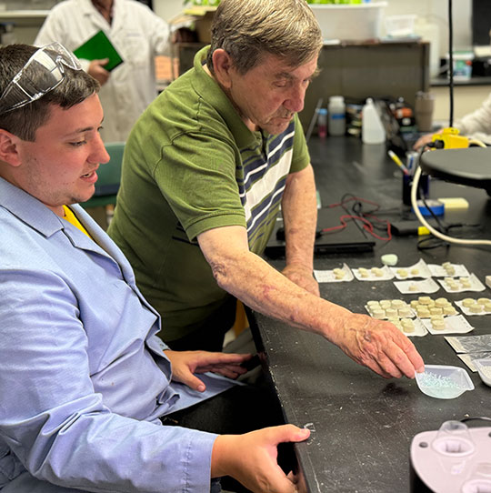man and student looking over discs made from waste glass
