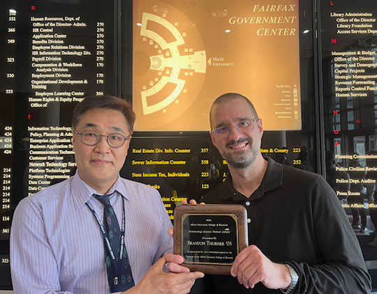 two men, holding a plaque