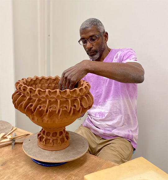 man sitting at a table, pinching out a pot