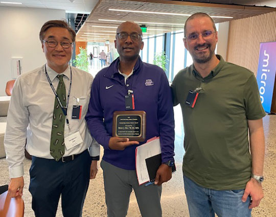 three men, one holding a plaque
