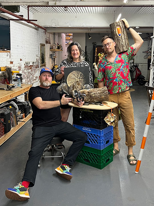 three people in an art studio displaying artwork