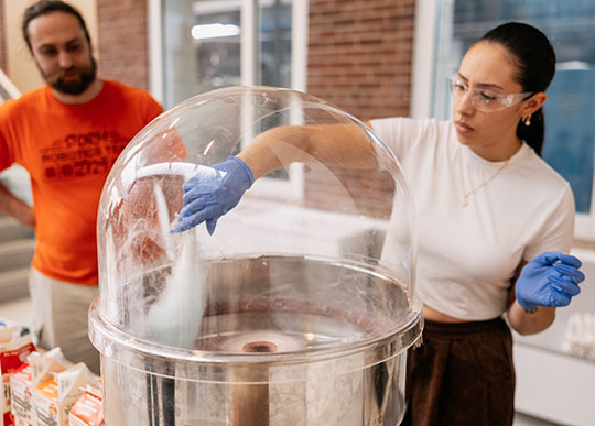 woman reaching into a glass dome making cotton candy