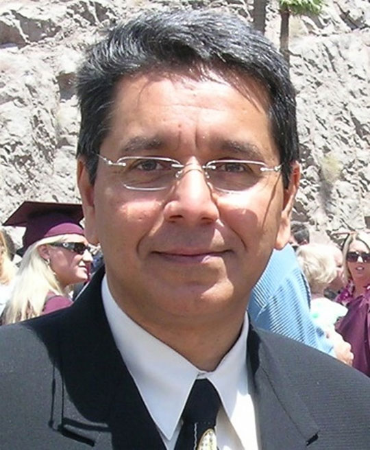 man in suit and tie, with glasses, smiling
