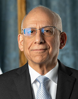 headshot of man with suit and tie and glasses