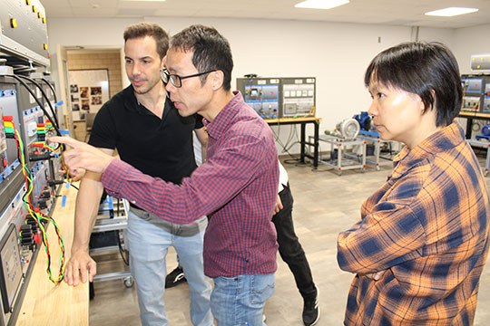 three people looking at a piece of electrical equipment