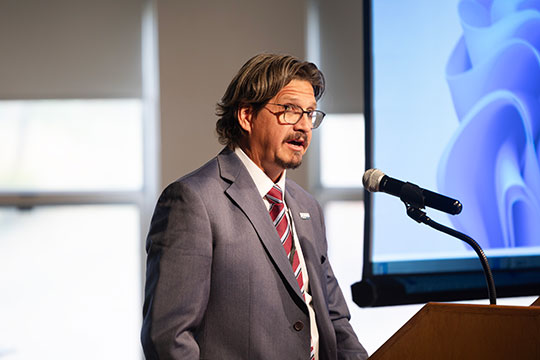 man with glasses speaking at podium