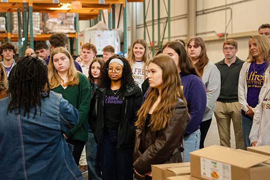 group of students listening to someone talk during a tour of a food bank