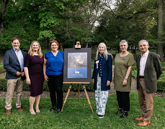 six people standing by a sign