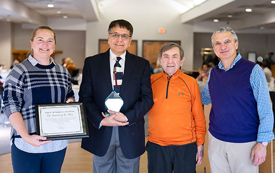 four people standing in a row smiling